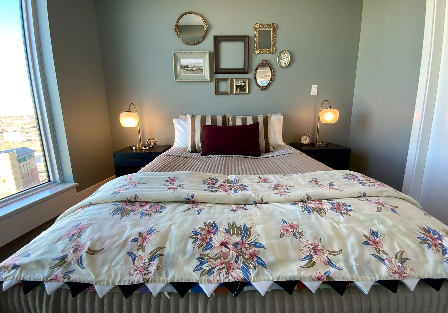 This green bedroom design features a handmade quilt and a salon-style gallery wall of antique picture frames, creating an eclectic space rich in character and warmth