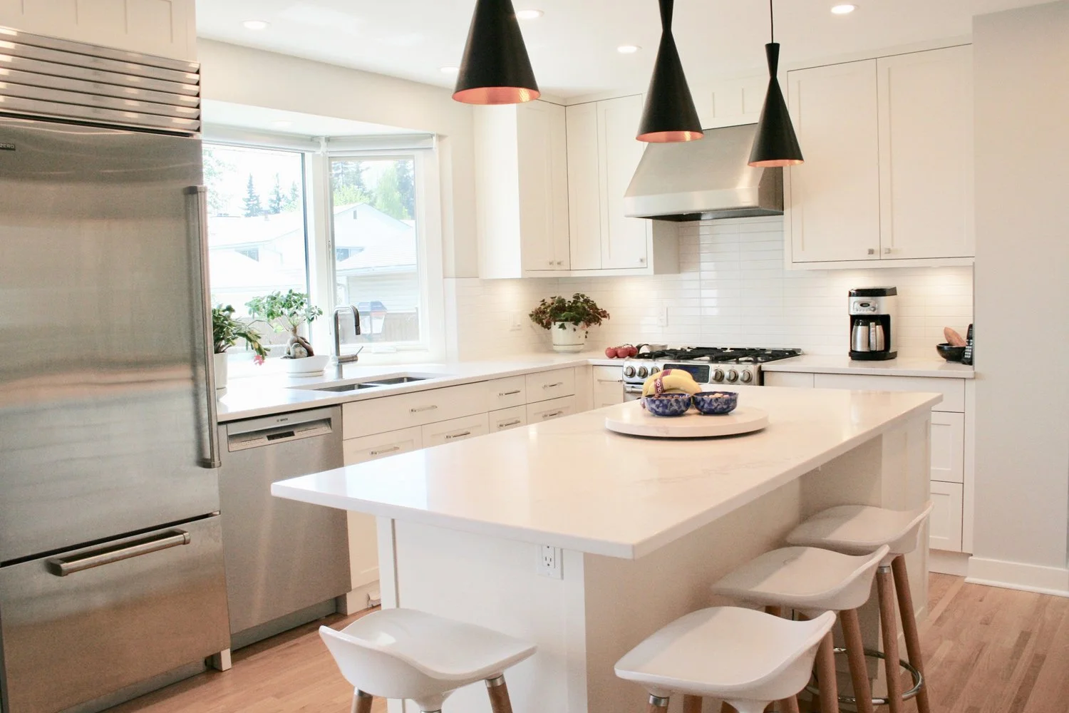 This transitional white kitchen features modern black pendant lighting over the island, blending classic style with contemporary accents.