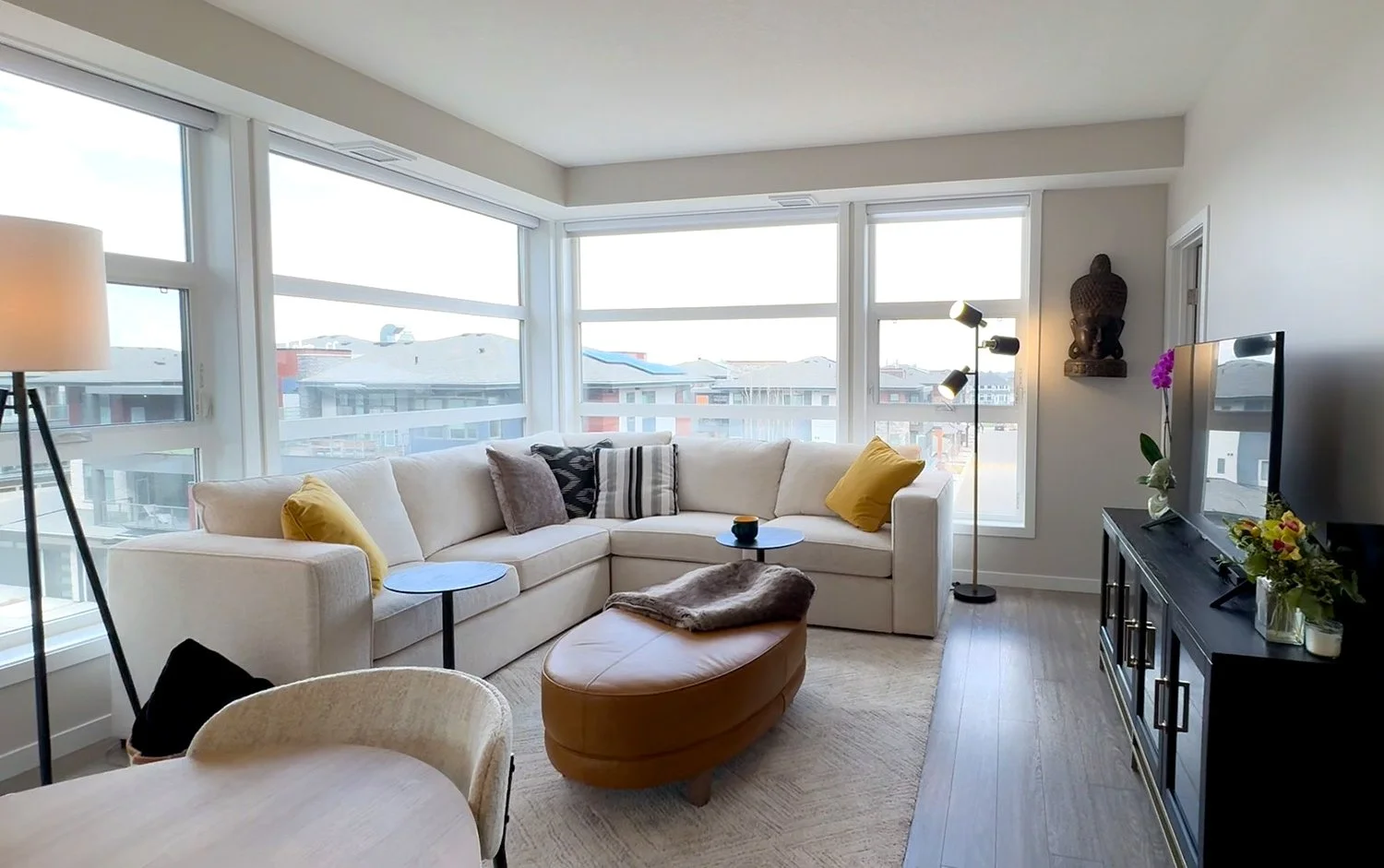 A small condo living room designed with space-saving, proportional furniture to maximize space. Using a neutral colour palette and colourful accents creates an open, airy feel with visual interest.