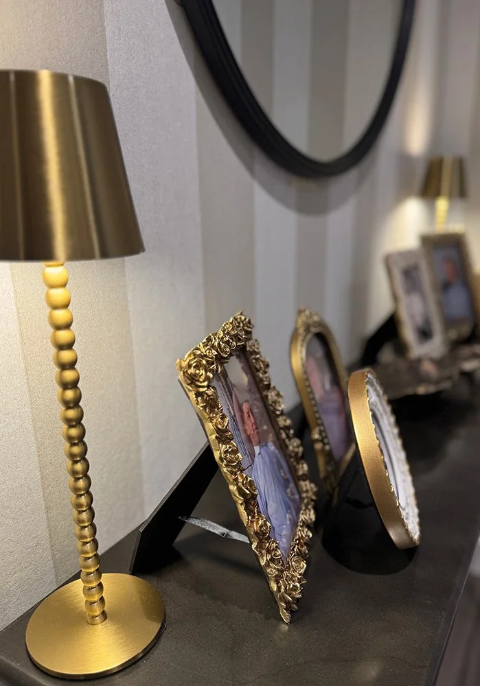 This welcoming entryway design features a mirror, layered lighting, and family photos in decorative frames, creating a warm and personalized foyer