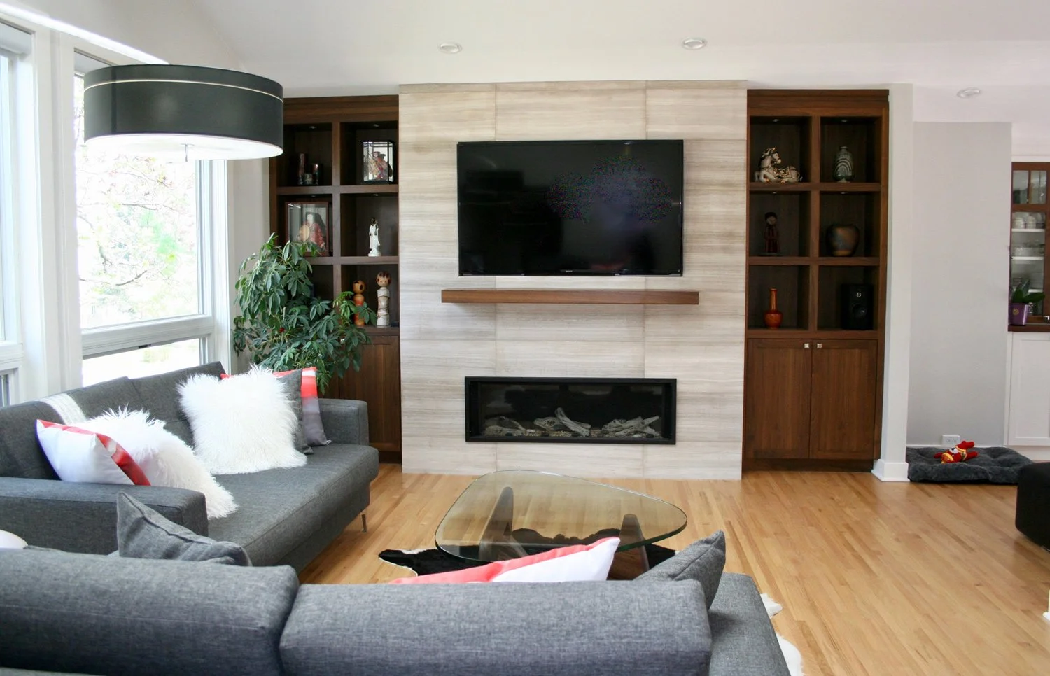 This modern living room features a limestone fireplace and inset TV wall framed by walnut display cabinets, combining natural materials with contemporary design.