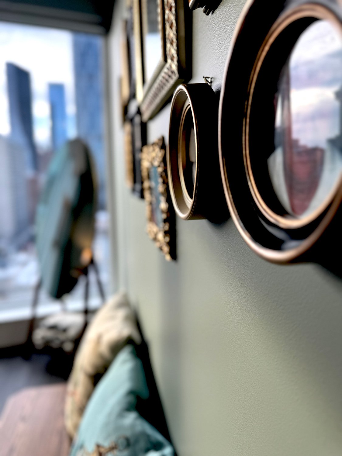 A green colour palette paired with antique gold frames and brocade accent pillows creates a layered, eclectic bedroom design full of character and warmth