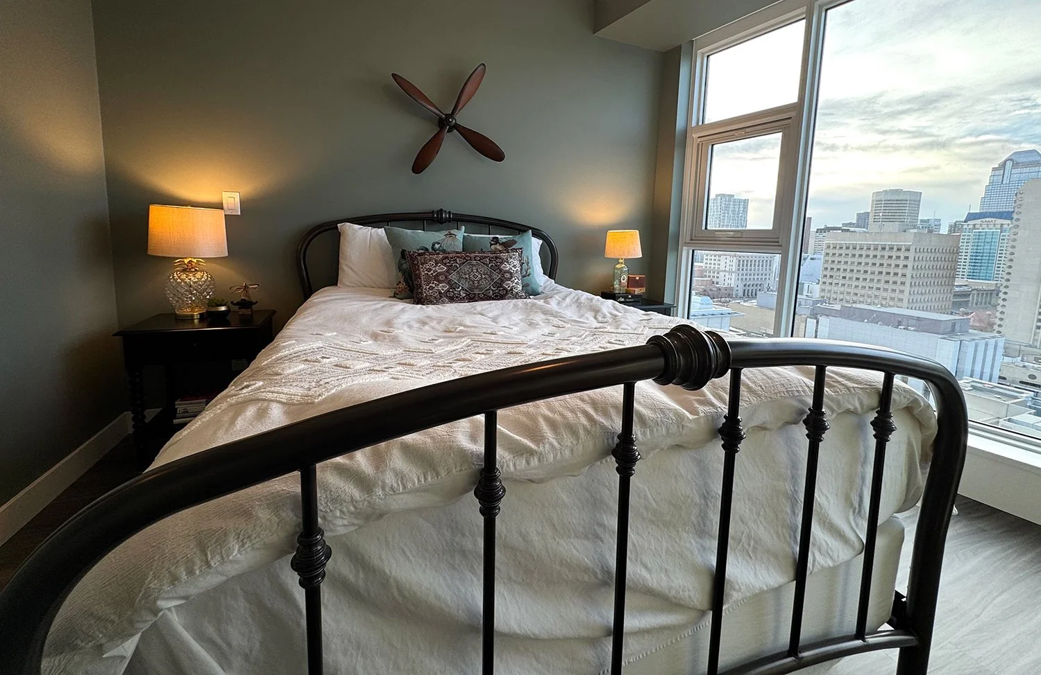 A green colour palette paired with antique furnishings and brocade accent pillows creates a layered, eclectic bedroom design full of character and warmth