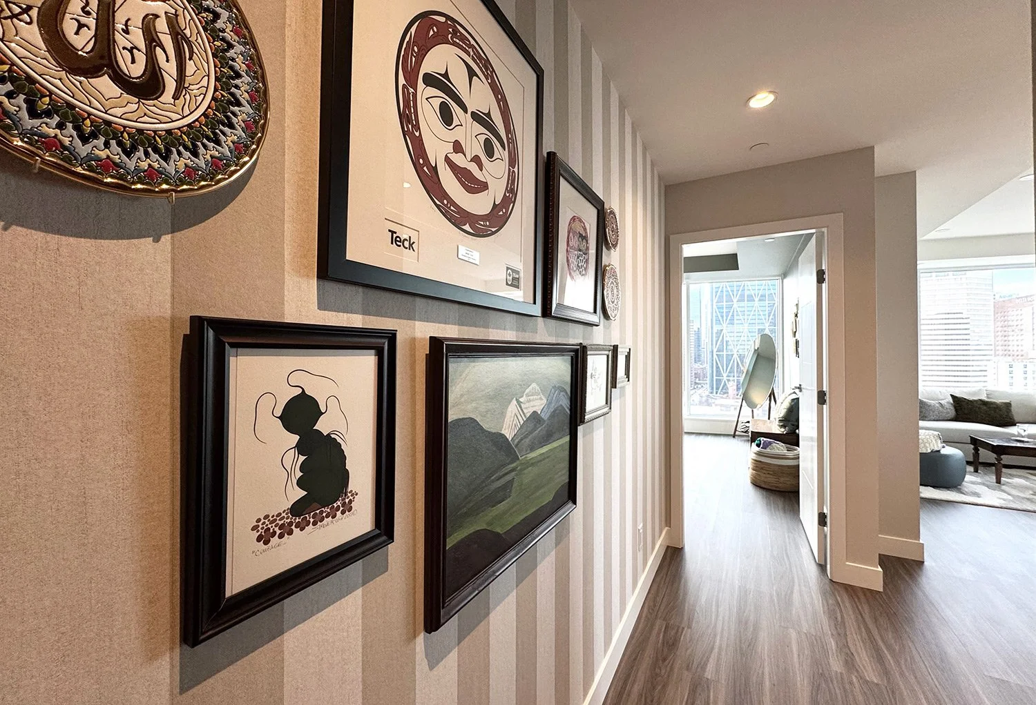 This eclectic condo design mixes antique furnishings with modern elements and striped wallpaper, creating a warm, stylish living space with stunning wraparound city views