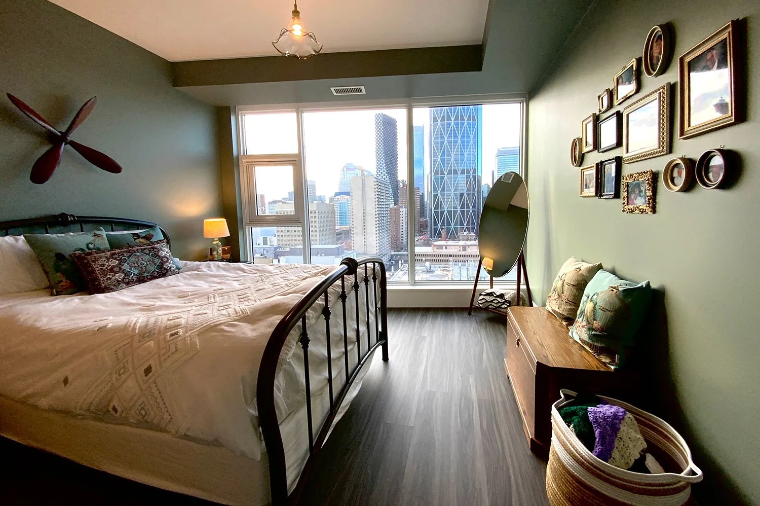 A green colour palette paired with antique furnishings and brocade accent pillows creates a layered, eclectic bedroom design full of character and warmth