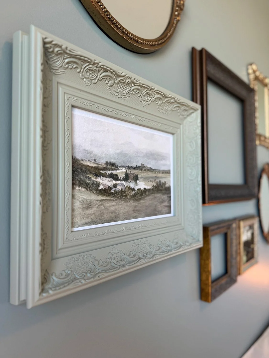 Wall installation of antique picture frames in a bedroom with a green colour palette creates for an eclectic bedroom design full of character and warmth