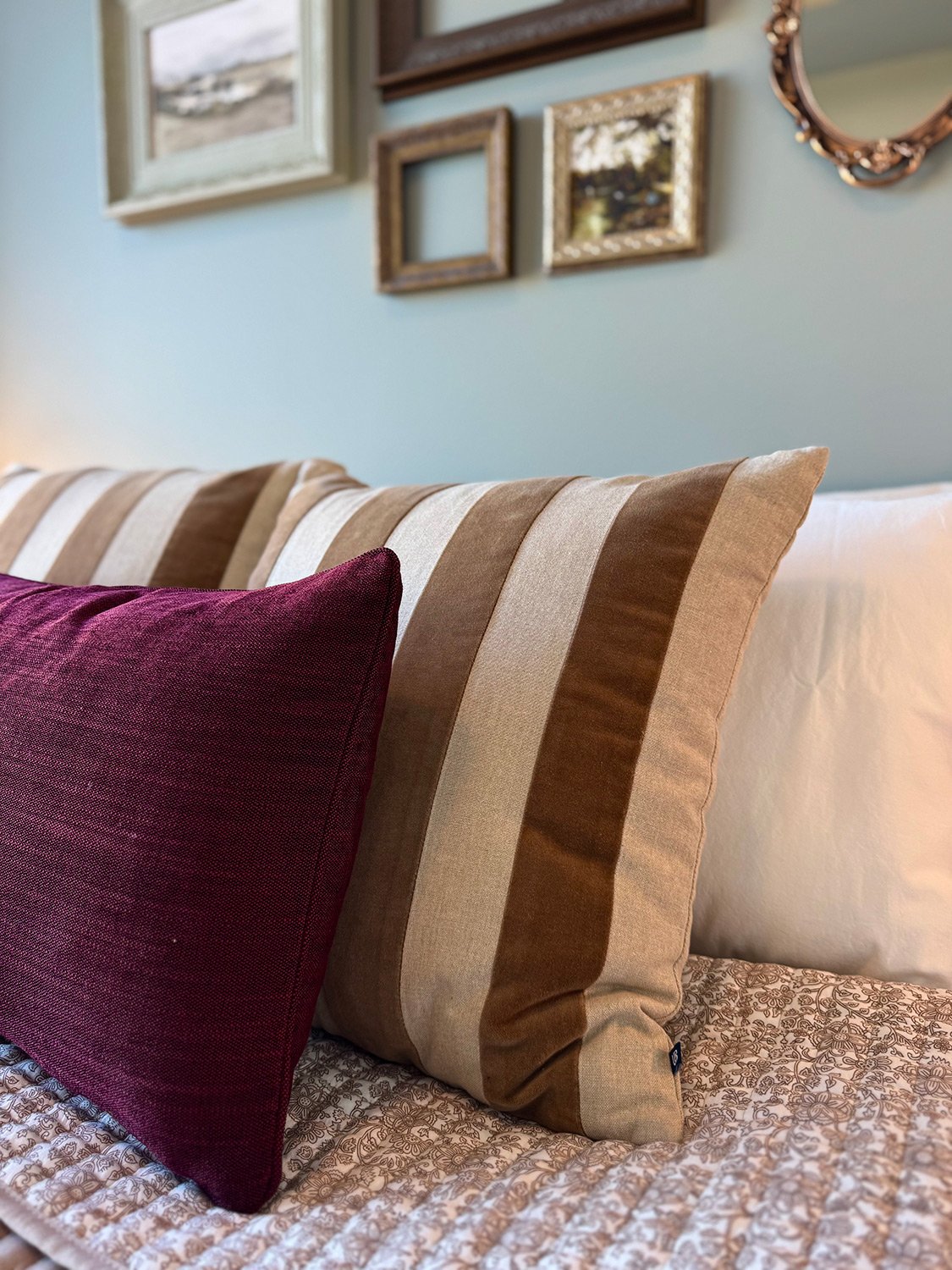 A green colour palette paired with antique gold frames, custom quilt and contrasting accent pillows creates a layered, eclectic bedroom design full of character and warmth