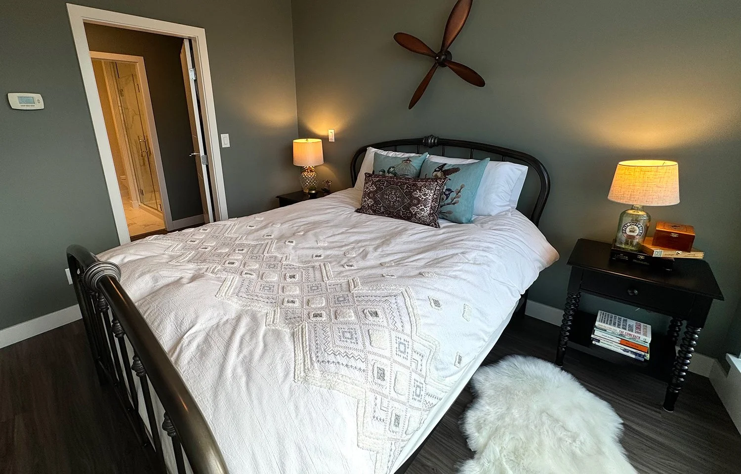 A green colour palette paired with antique furnishings and brocade accent pillows creates a layered, eclectic bedroom design full of character and warmth