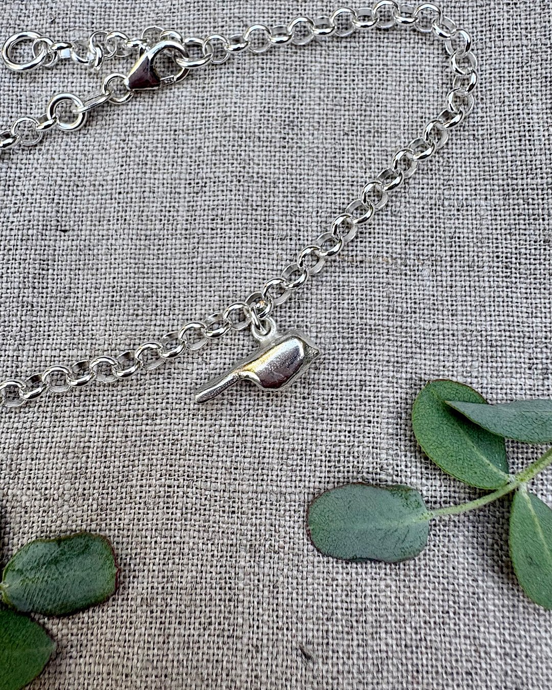 sterling silver bracelet with bird charm - handmade jewellery in uk on natural background