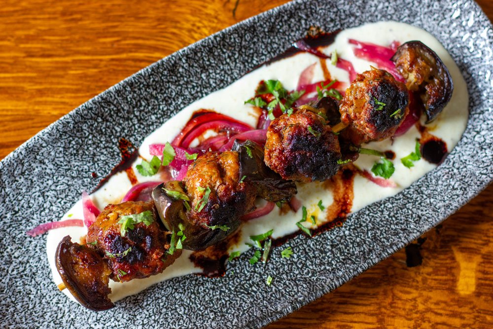A spiced lamb &amp; aubergine kebab served with pickled red onion &amp; ajo blanco
