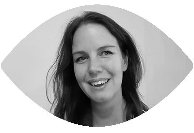Portret van een lachende vrouw met lang, donker haar, op de achtergrond in zwart-wit.