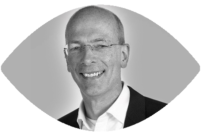 Portret van een glimlachende man met bril, gesneden in een ovale vorm, zwart-witte foto.