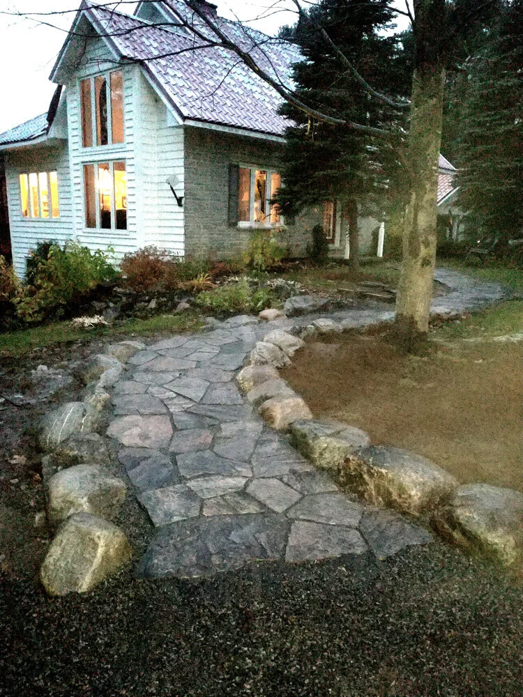 Elegant stone walkway with rough stone boarder along a beautiful Muskoka cottage. 