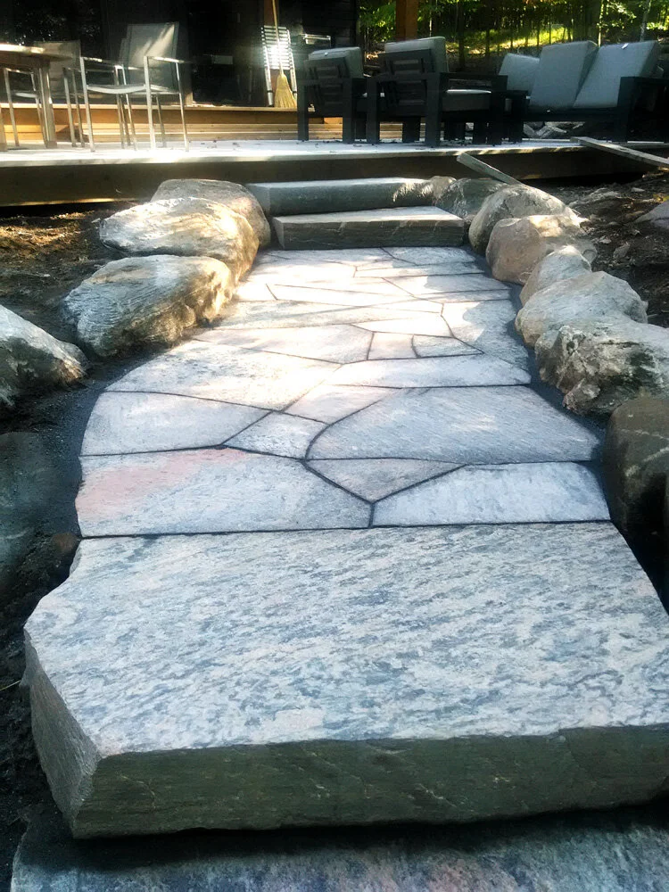 Rough cut thick flagstone walkway and stairs with natural rock border. 