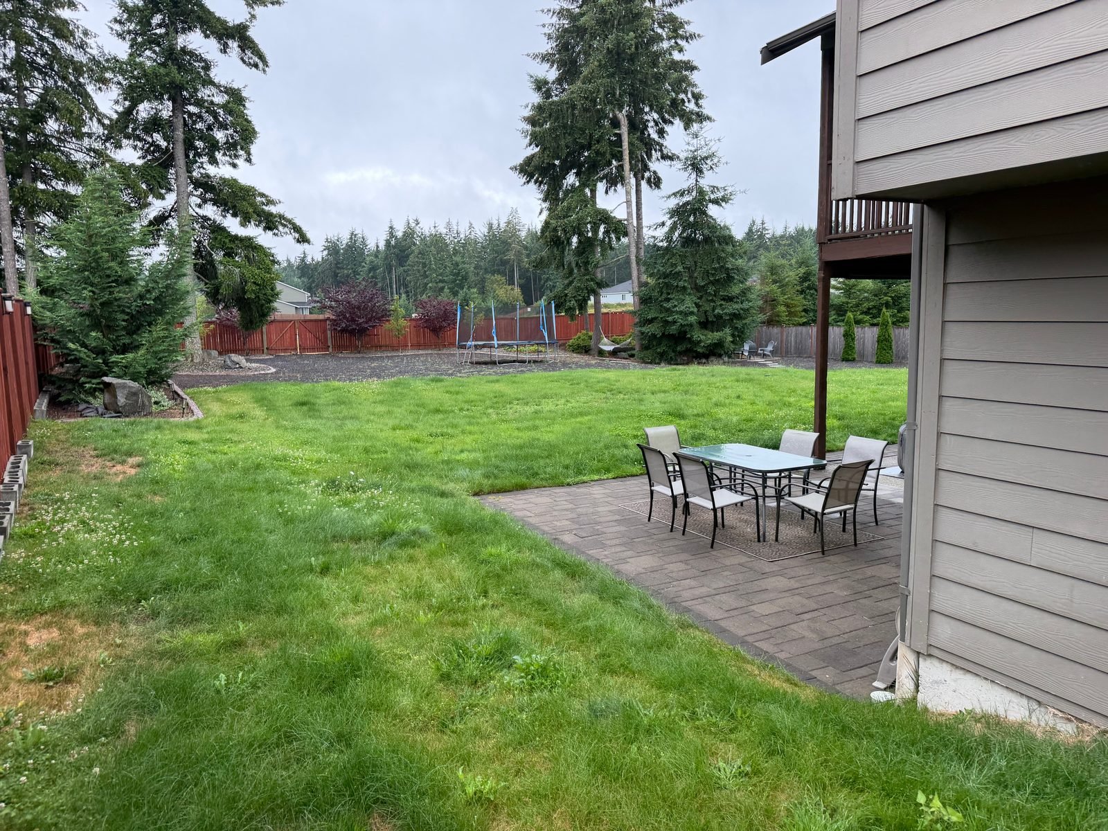 Backyard paver patio with an outdoor dining set beside a lawn in Olympia, WA