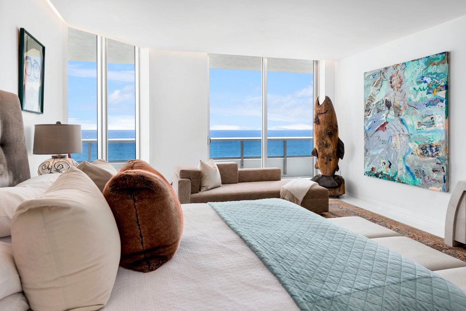 Luxury oceanfront bedroom with large windows, modern decor, and abstract art. 1 OAK Studios, photo, video, drone, real estate photography and video.