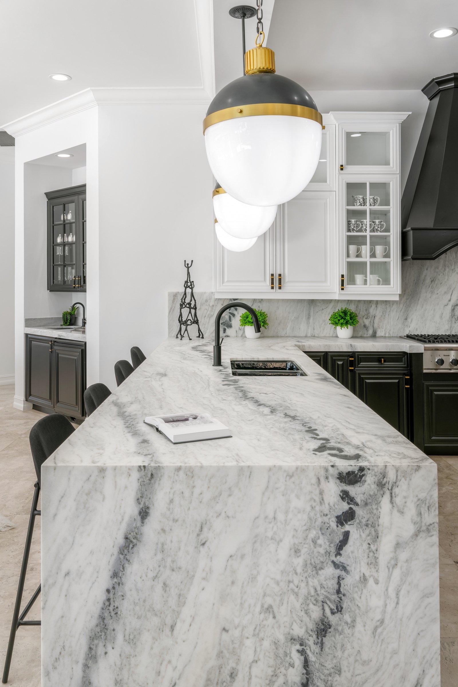 Modern kitchen with marble island, pendant lights, black and white cabinets, and stainless steel appliances. 1 OAK Studios, photo, video, drone, real estate photography and video.