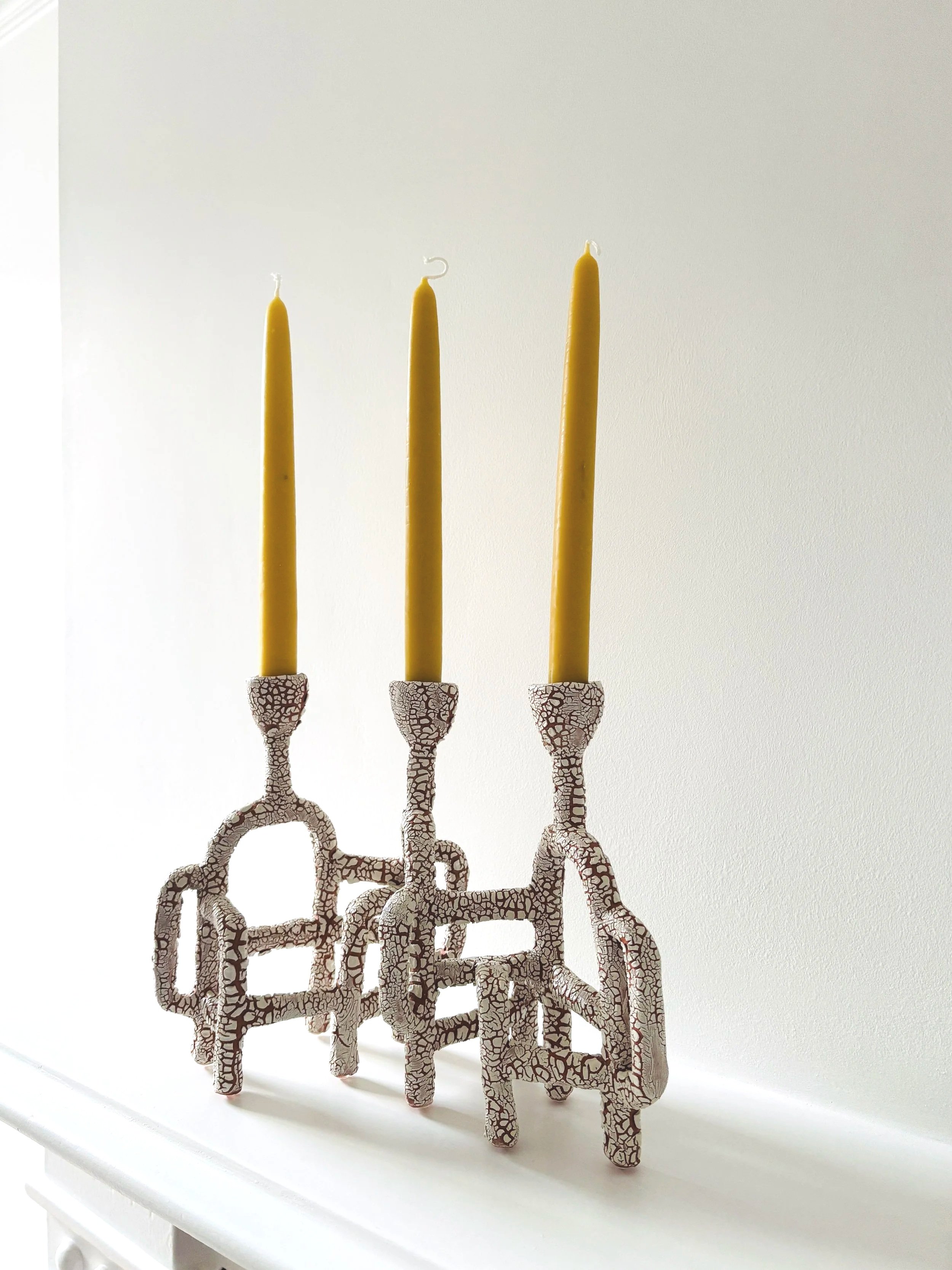Decorative candles with a giraffe pattern base and tall yellow candles on top, placed on a white surface.