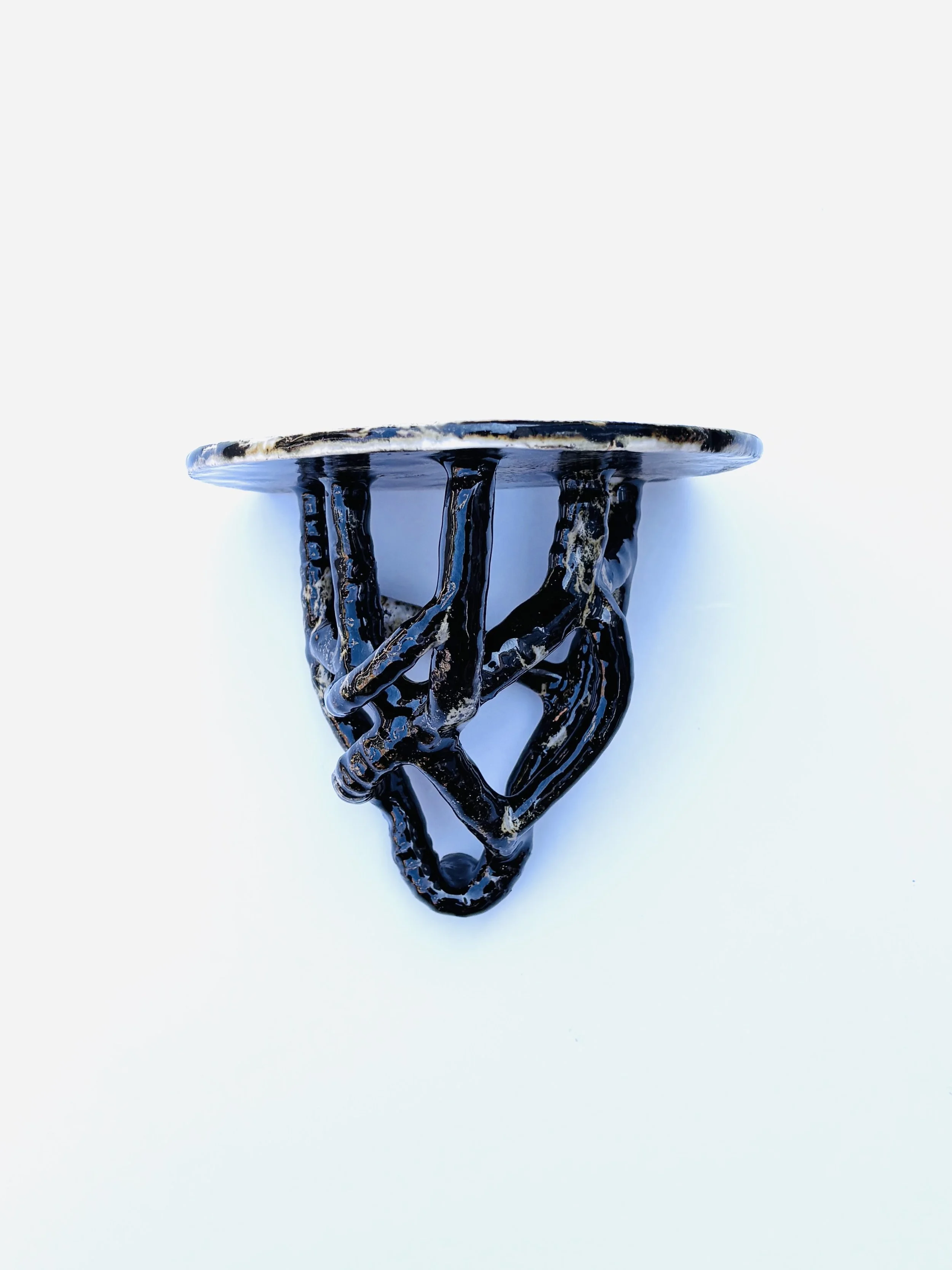 A decorative black and white ceramic sculpture resembling a stylized plant or abstract figure on a white background.