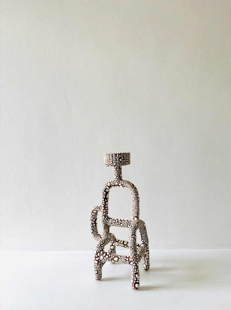 A decorative sculpture of a dog made of connected circular and geometric pieces, placed on a white surface against a plain white wall.
