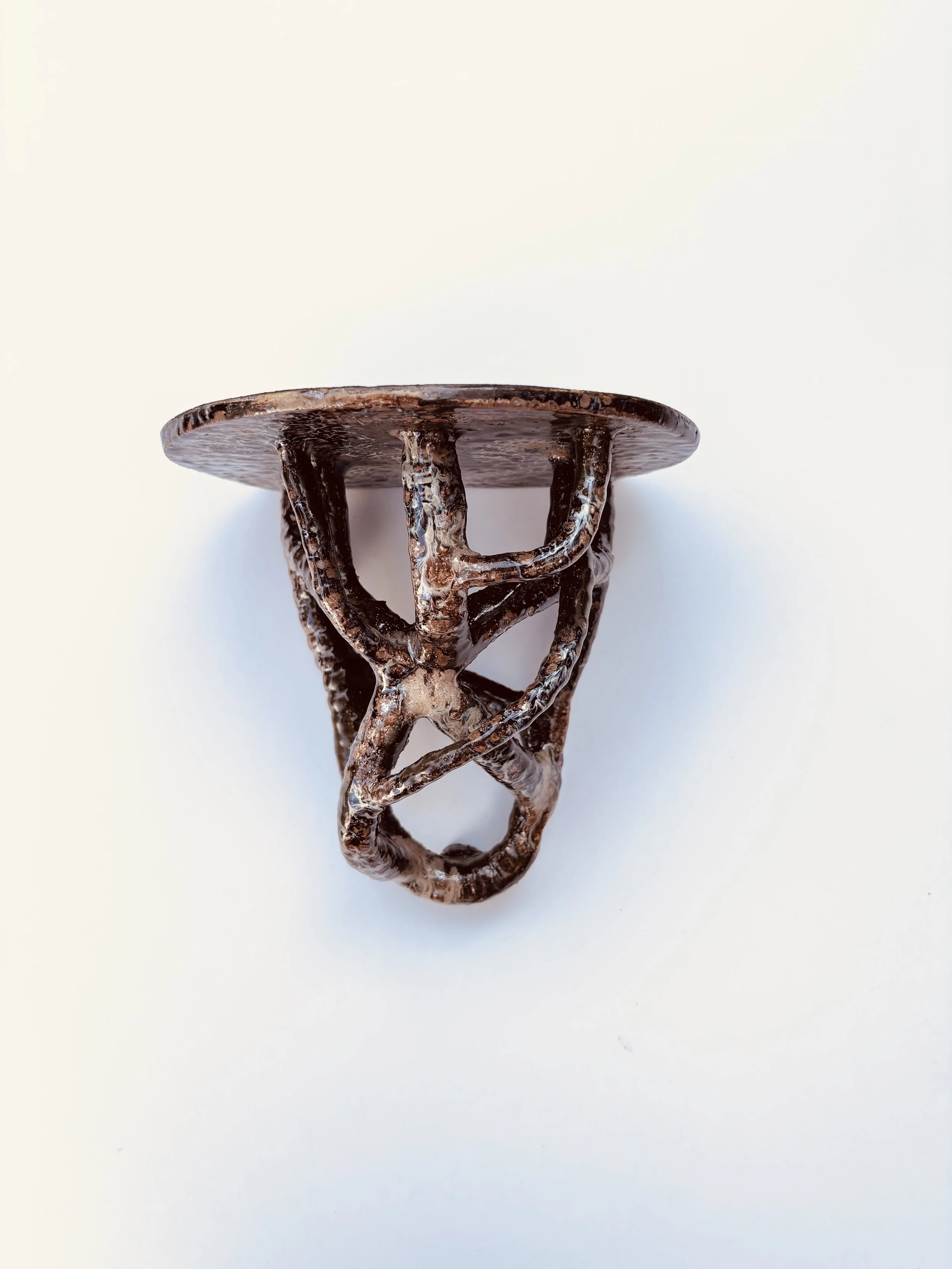 Caramel and brown glazed ceramic corbel style shelf against a plain white background.