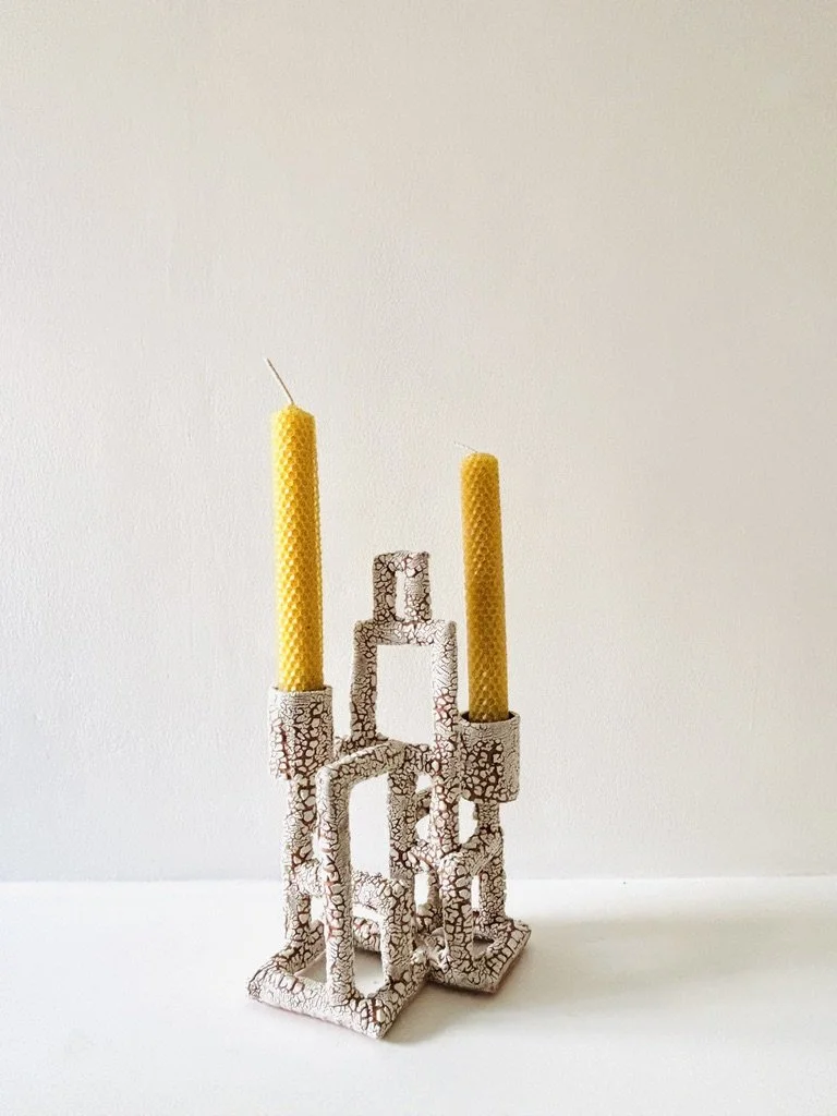 Decorative ceramic candle holder with acracked glaze pattern holding two yellow pillar candles.