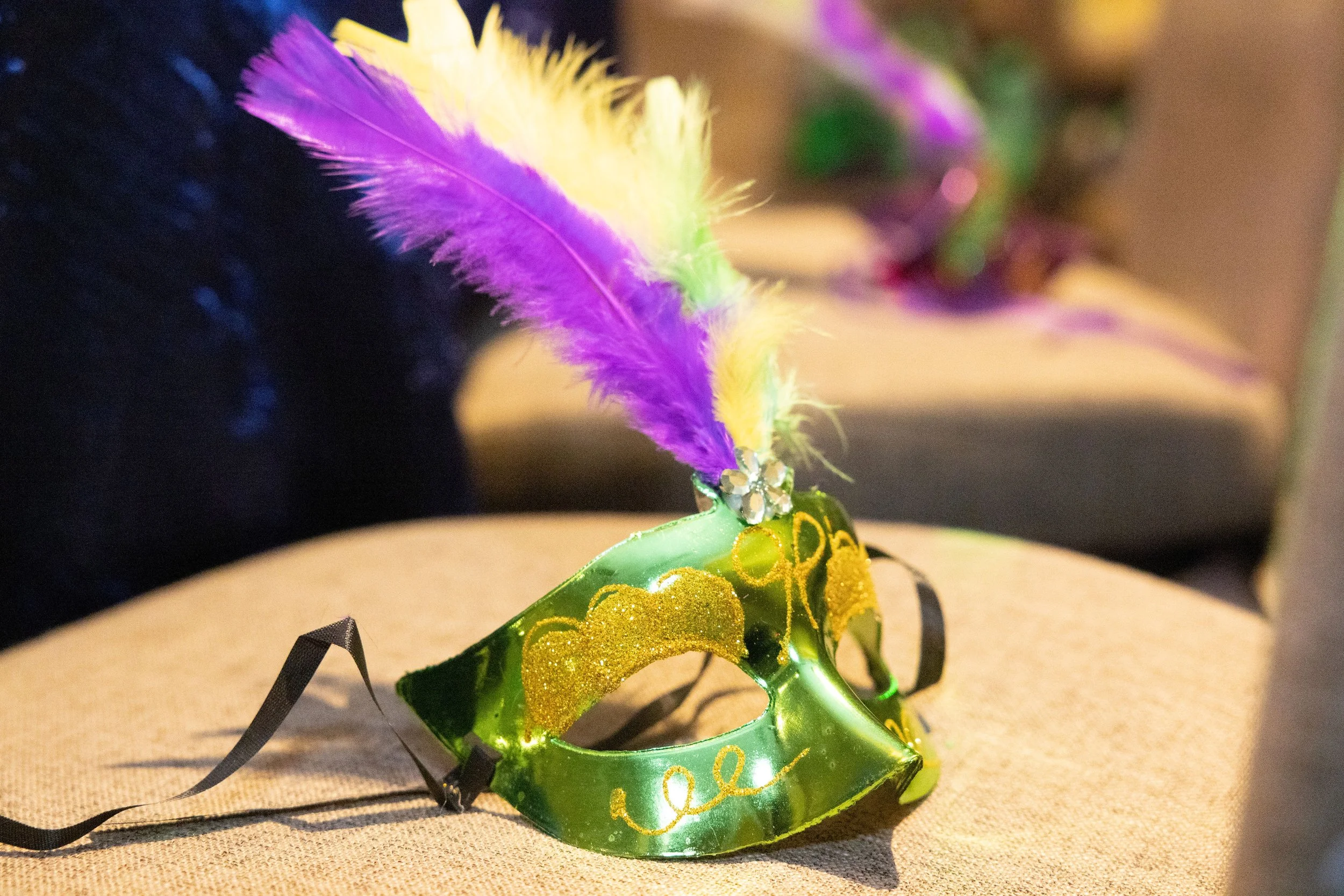 Green mask with gold accents and purple, yellow, and green feathers