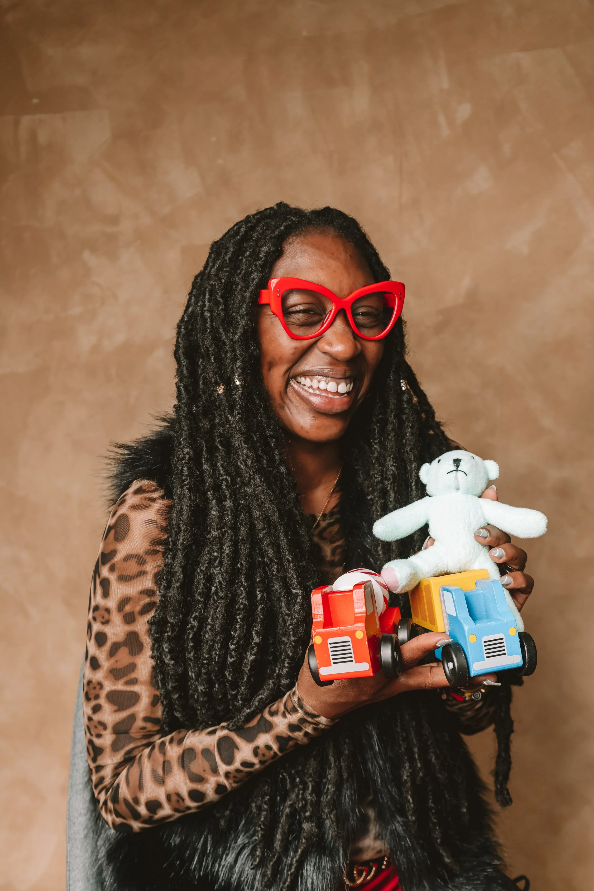 Trinity Washington University Alumna Alicia Price holds two toy cars and a small stuffed bear representing her project, "It Takes a Village."
