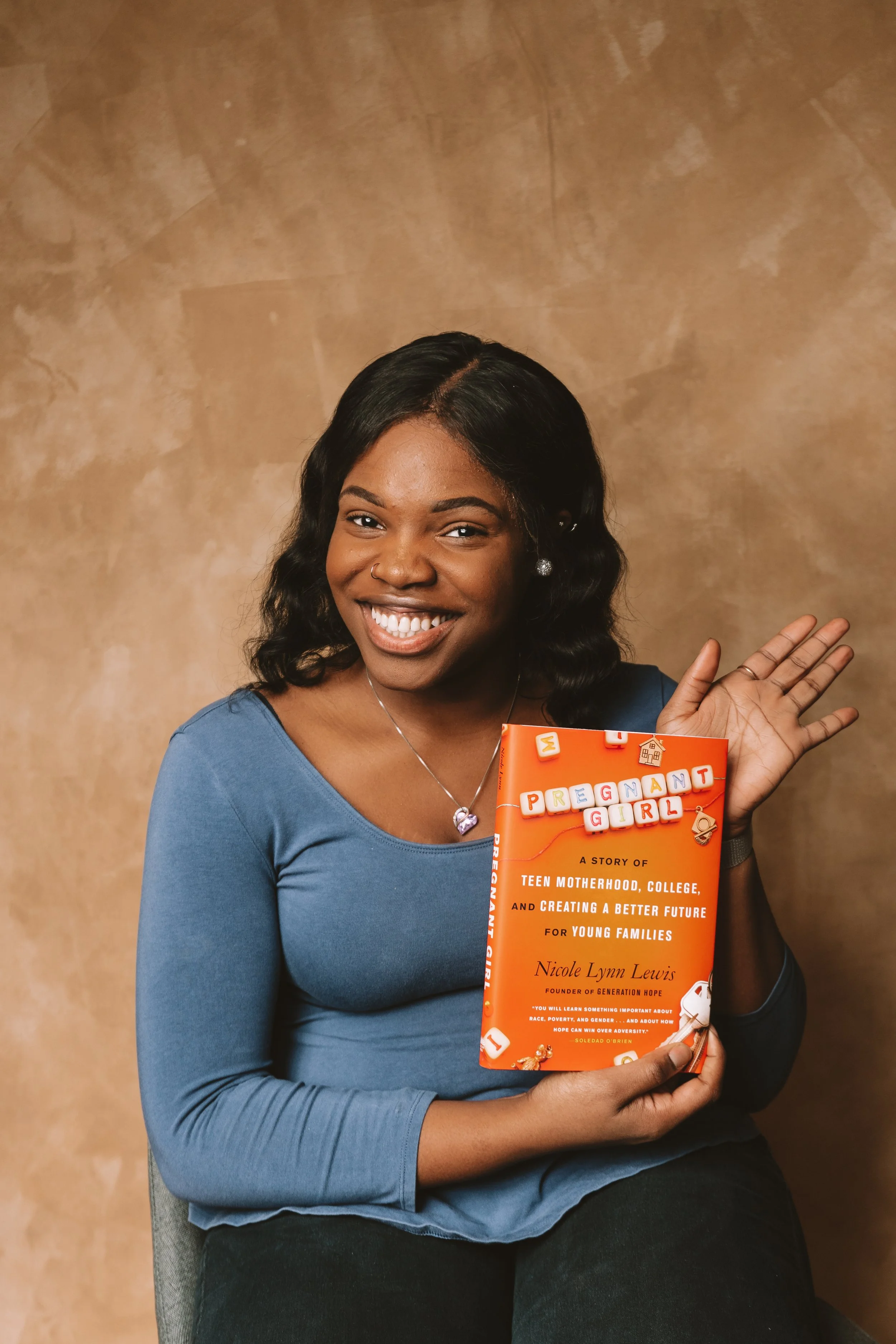 George Washington University Alumna Bri Whitfield holds a copy of "Pregnant Girl" by Nicole Lynn Lewis to represent her project, "Book Club and Dinner."