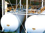 Deux grands réservoirs cylindriques blancs avec des structures métalliques et des tuyaux.