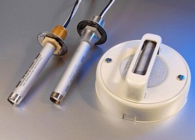 Sondes thermiques en métal argenté et capteur circulaire blanc, fond gris.