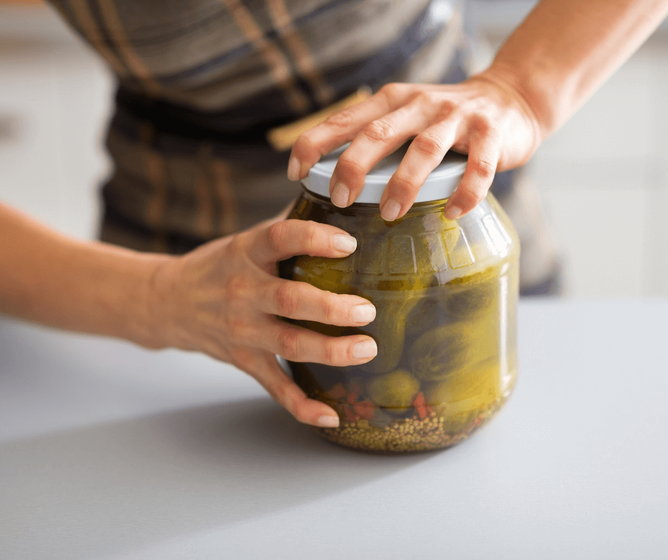 InHouse Pilates blog The benefits of being active image woman struggling to open a jar of pickles.