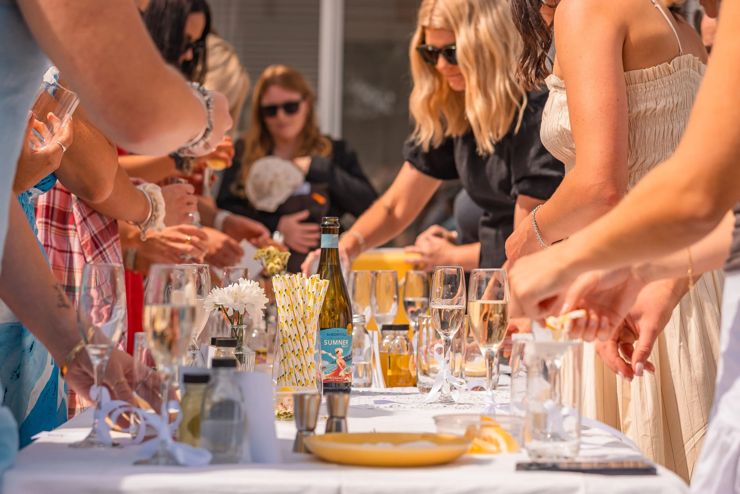 People gathered around a table with drinks and decorations, participating in a toast or celebration.