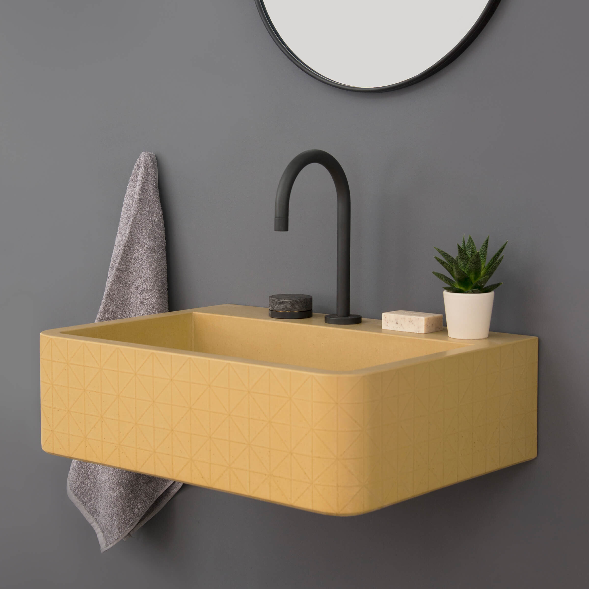Yellow wall-mounted concrete washbasin sink with a decorative geometric surface pattern and contemporary bathroom accessories..  (Copy)