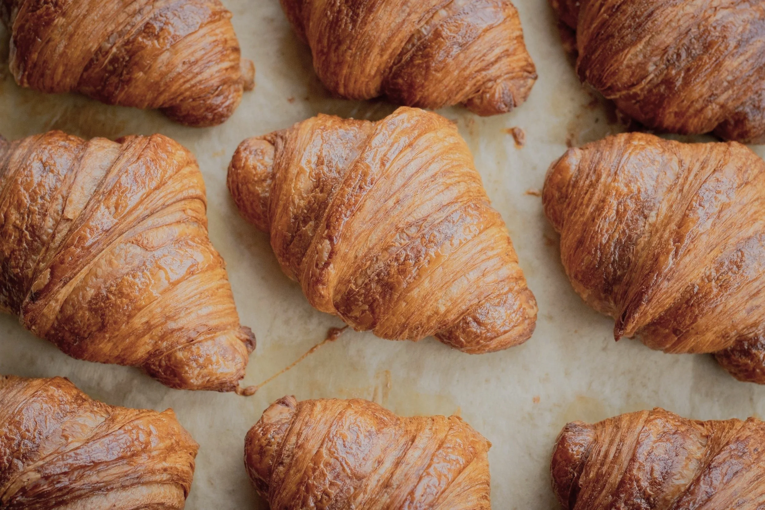 Färska croissanter på ett bakplåtspapper.