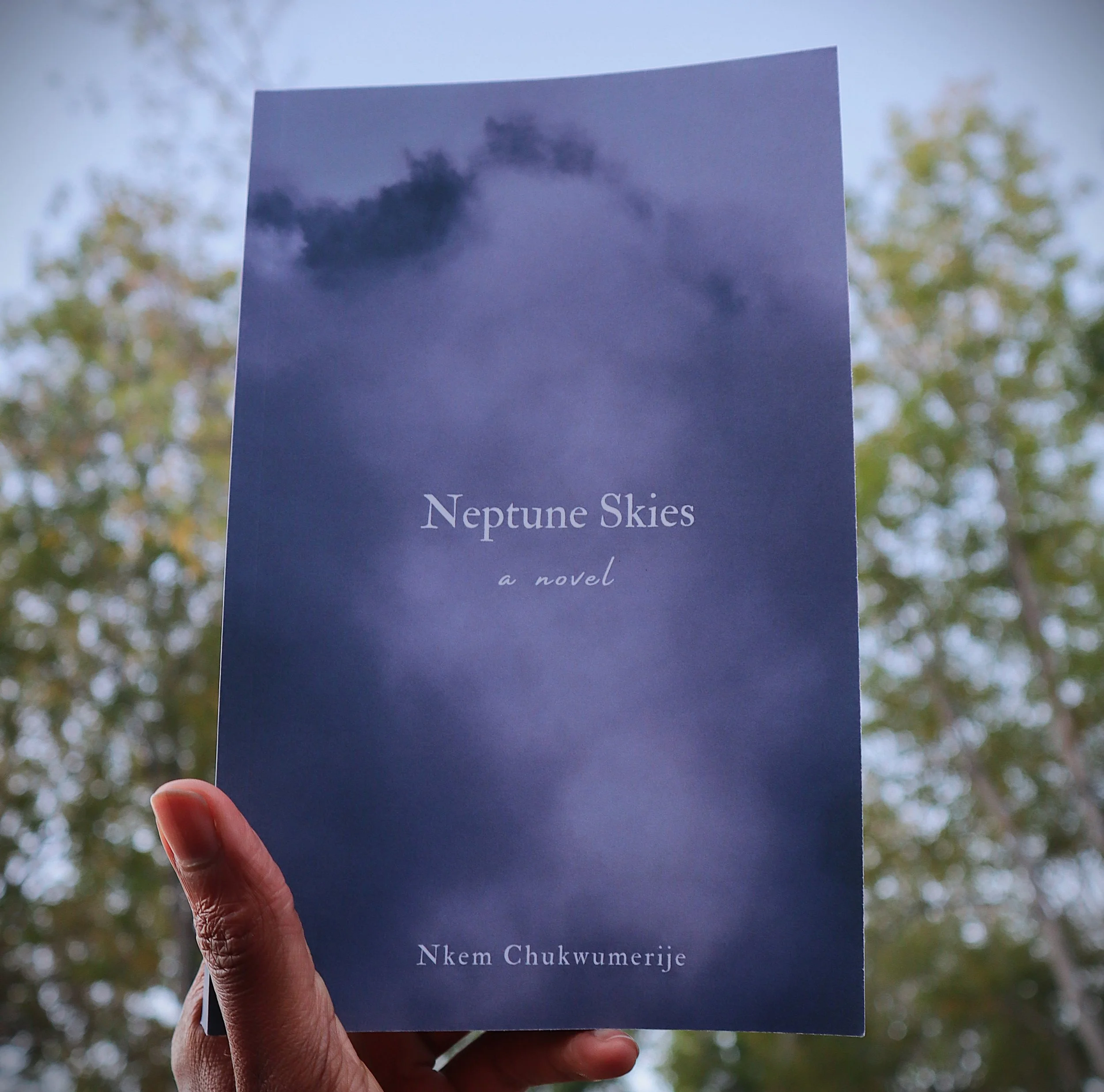 a blue book against he background of a sky with green leaves