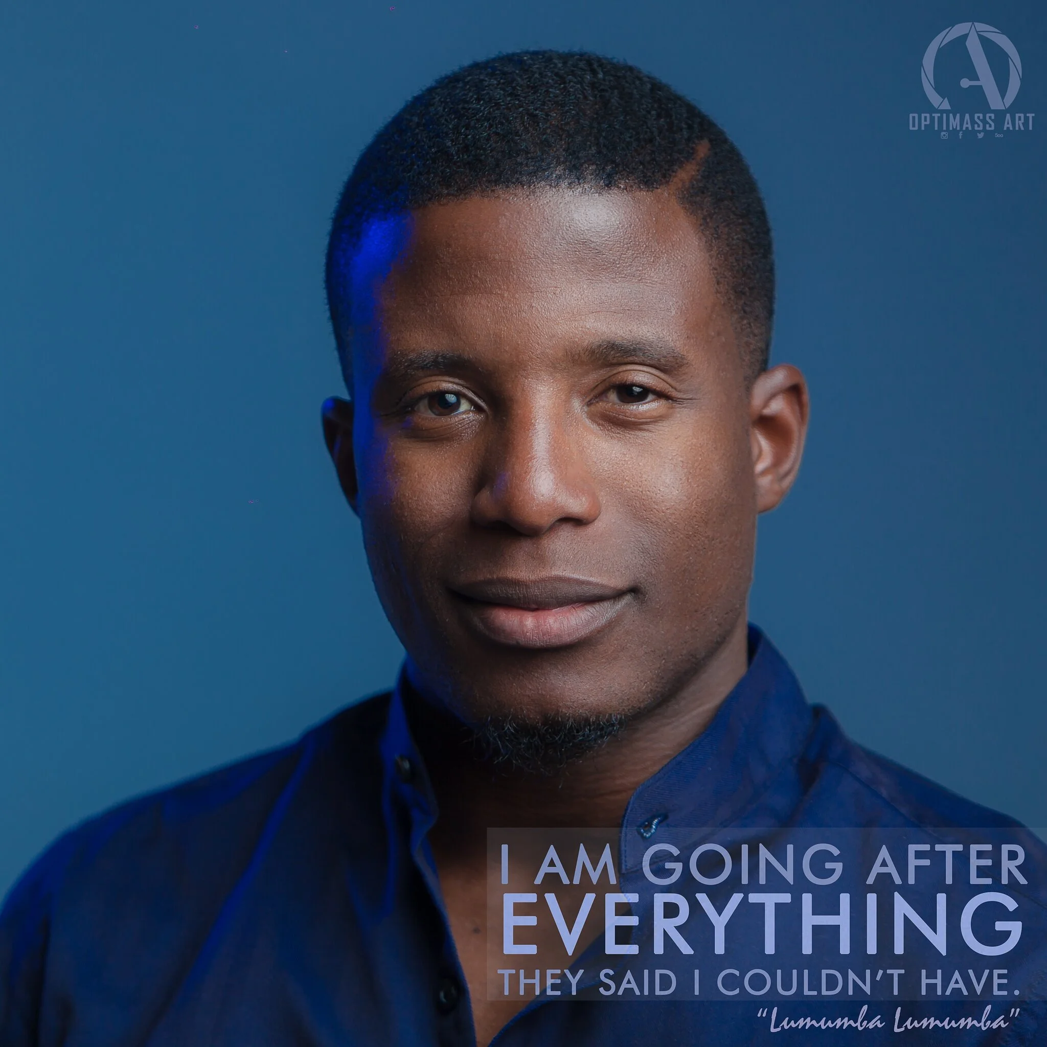 Close-up portrait of a young man with short hair, wearing a dark blue shirt, against a blue background.