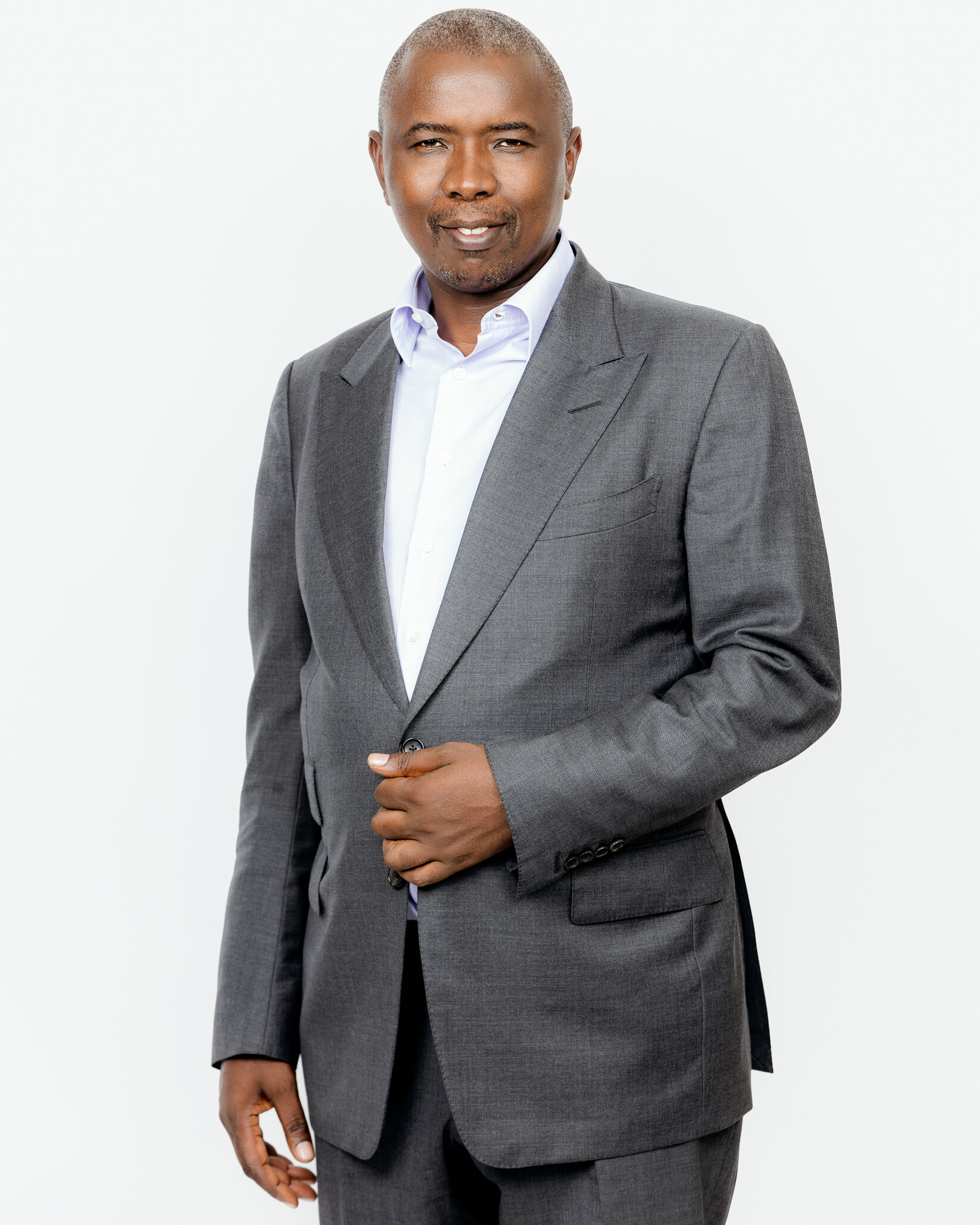 Portrait of a middle-aged Black man in a gray suit and white shirt, standing against a plain white background.