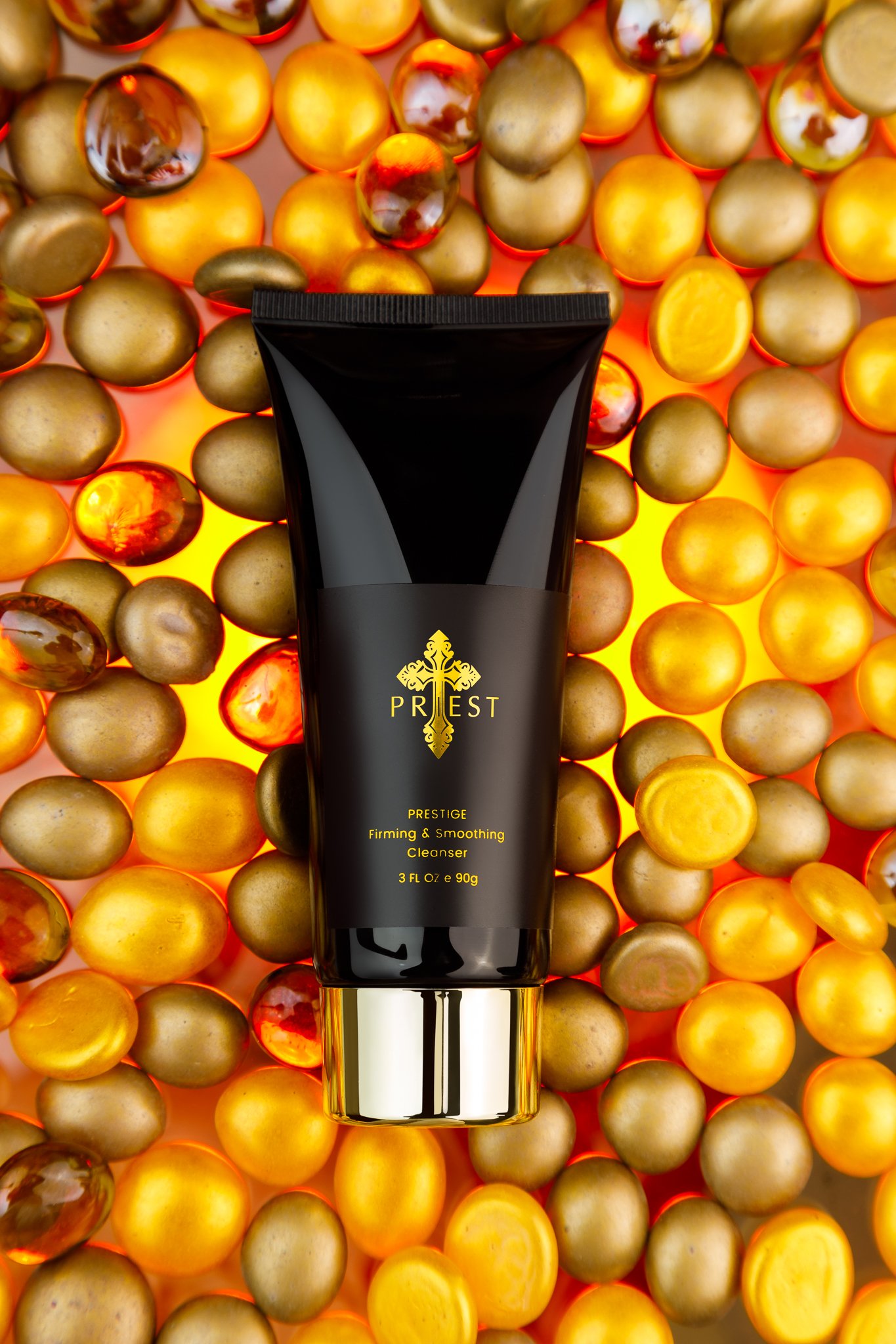 A black tube of PREST Prestige firming and soothing cleanser placed on a background of gold and red decorative spheres.