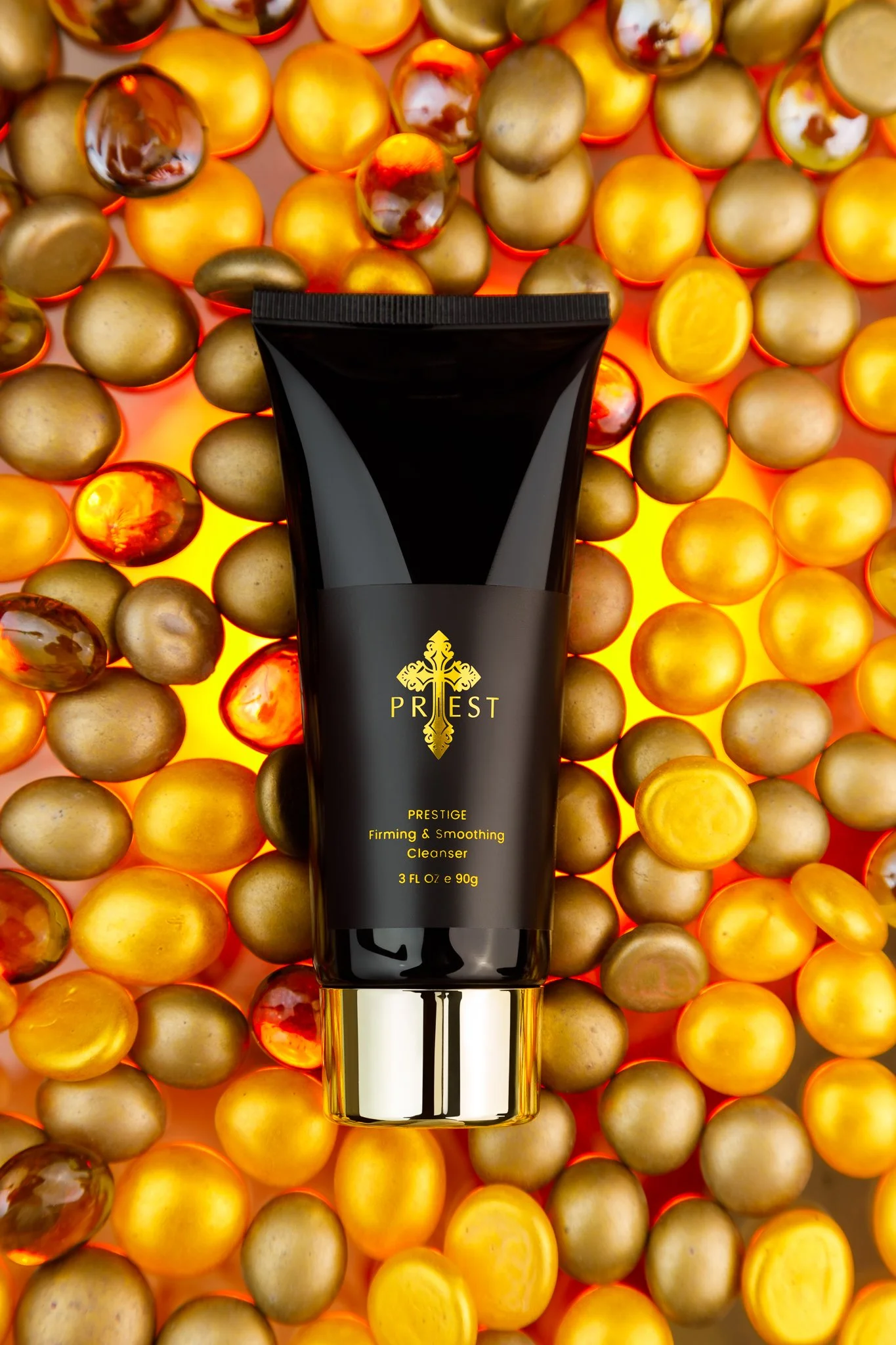 A black tube of PREST prestige firming and smoothing cleanser surrounded by numerous gold, amber, and red decorative balls with a glowing orange background.