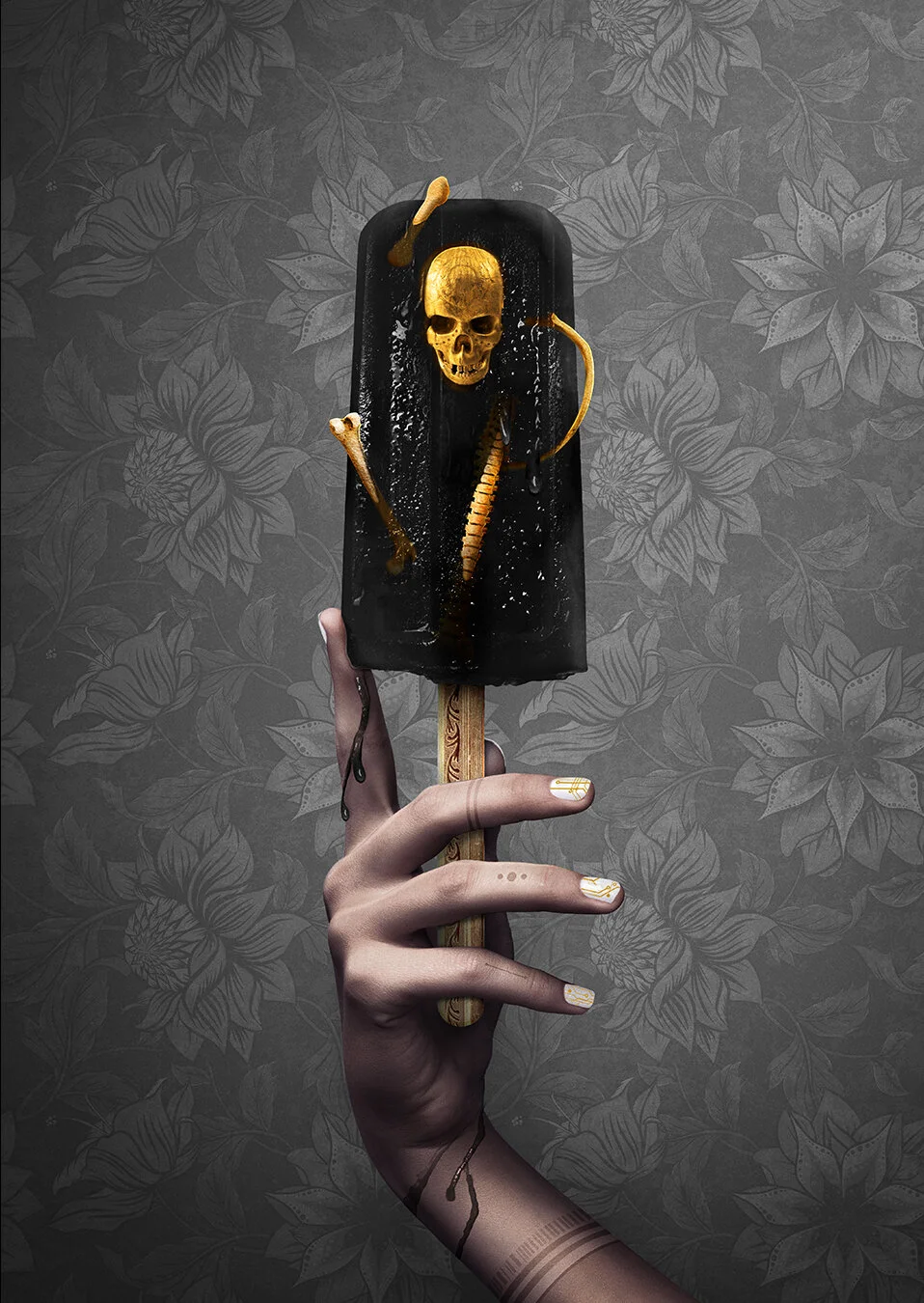 A person's hand with tattoo and decorated nails holding a black ice cream popsicle mold with a skull and bones inside, against a patterned gray background.