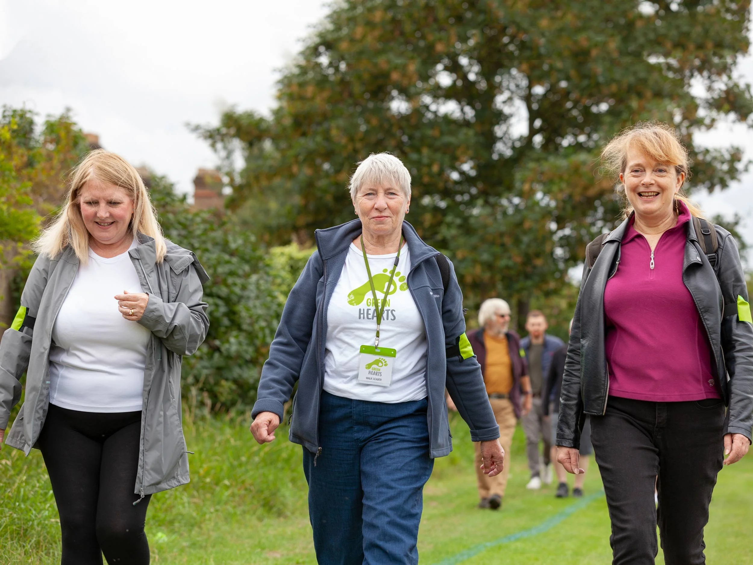 Group of women walking in a park during daytime, smiling and enjoying an outdoor event.