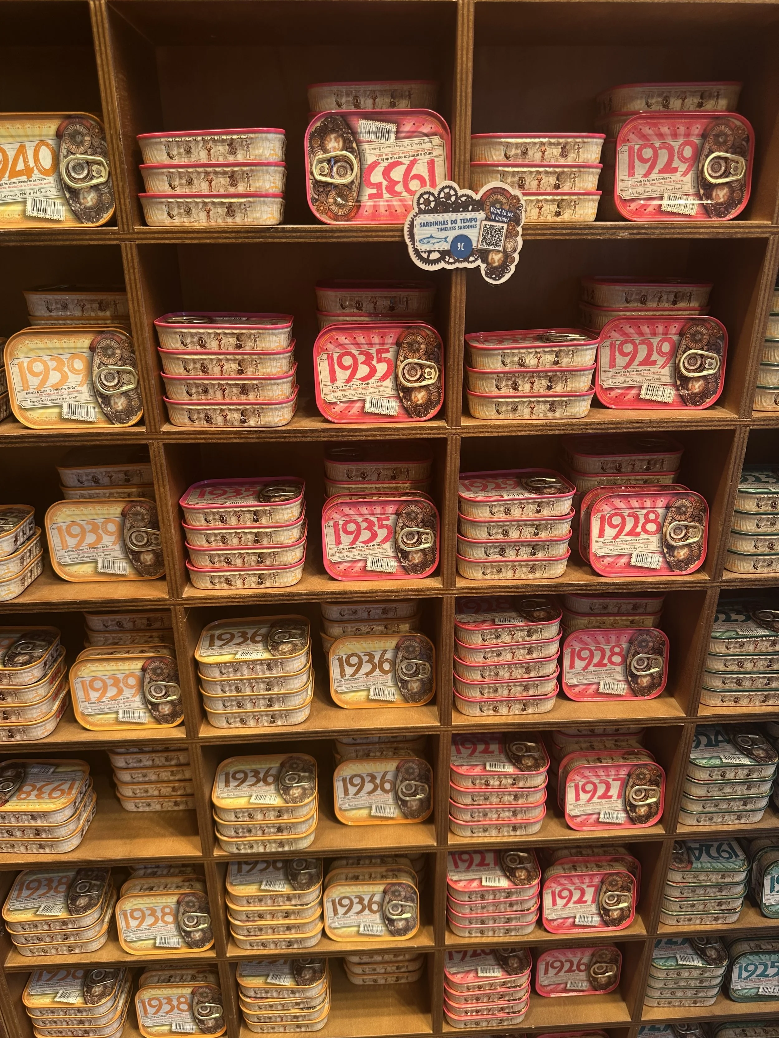 Shelves filled with stacks of canned sardines labeled with different years from 1921 to 1940.