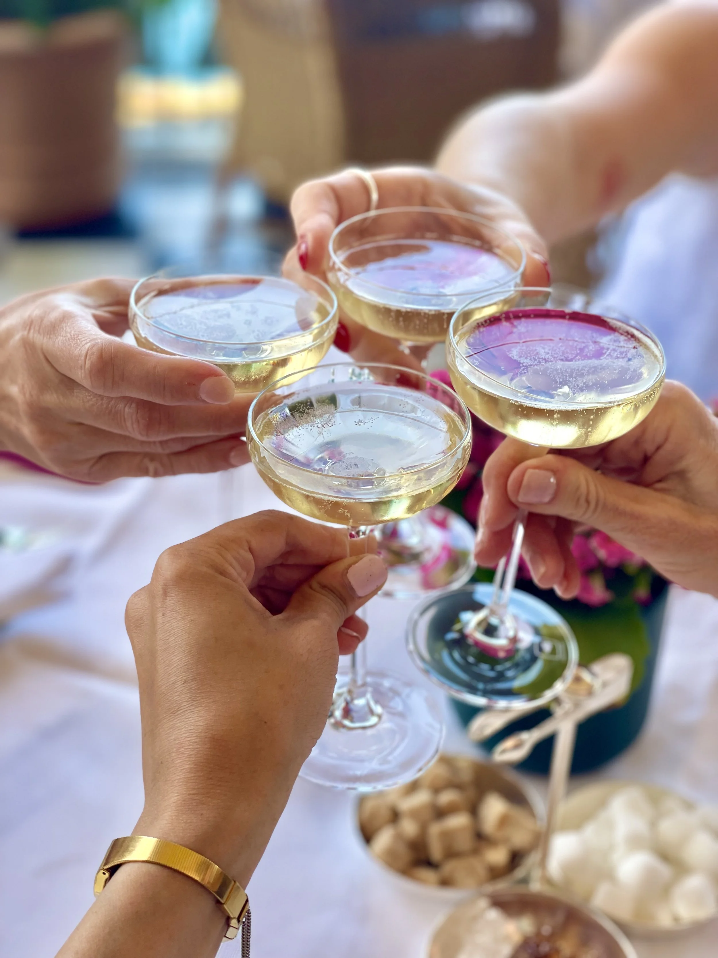 Four people holding glasses of champagne in a toast at a celebration.