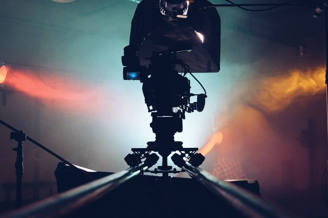  Close-up of a camera on a dolly track with colorful lighting in the background. 