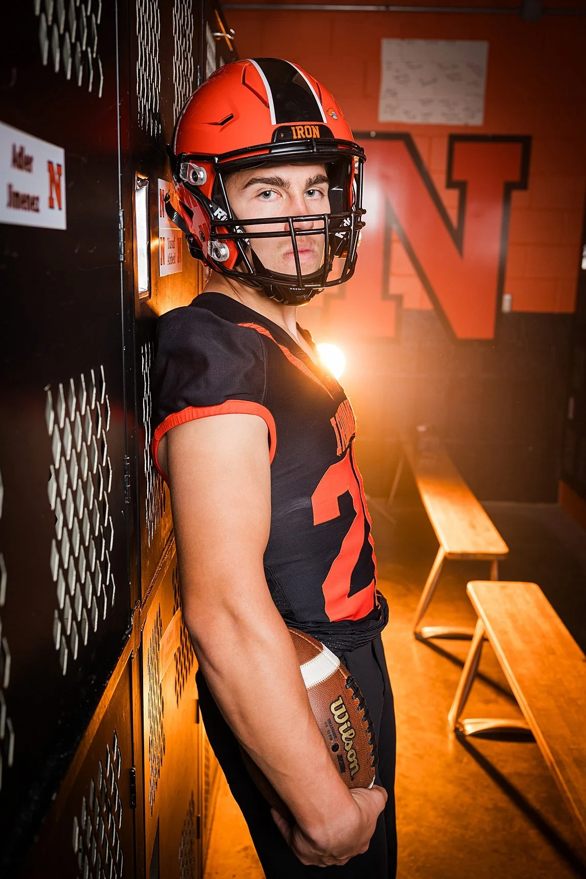 high school senior boy football player in dramatic sport lighting with fog smoke and lights senior portraits Bloomington IL