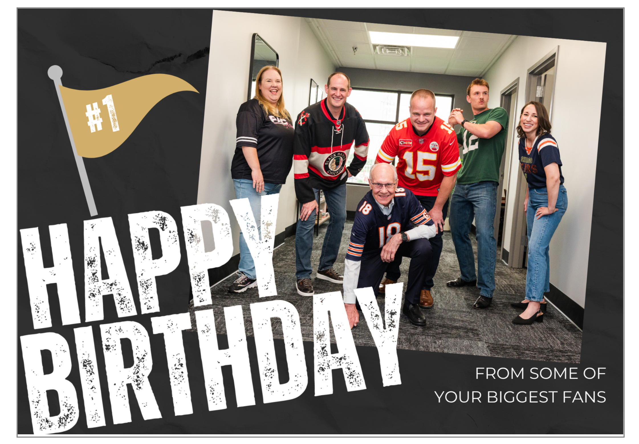 Group of people celebrating a birthday, with some wearing football jerseys, in an office hallway with a sign that says 'Happy Birthday' and an illustration of a gold flag with '#1' on it.