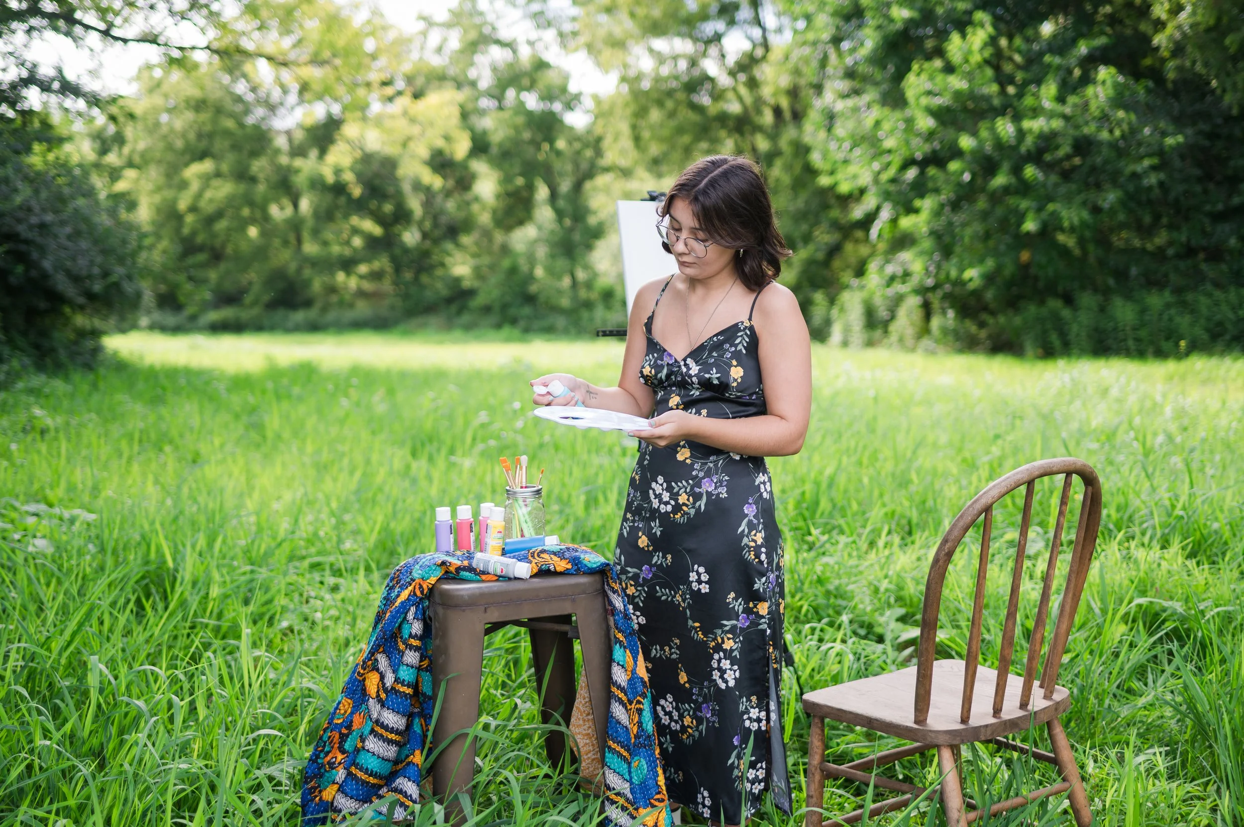 Creative senior portrait of a teen artist with easel and paint in an outdoor field, Central Illinois