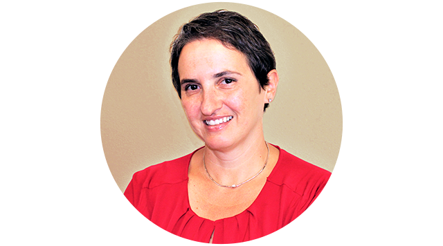 A woman with short dark hair, wearing a red blouse, smiling at the camera against a plain beige background.