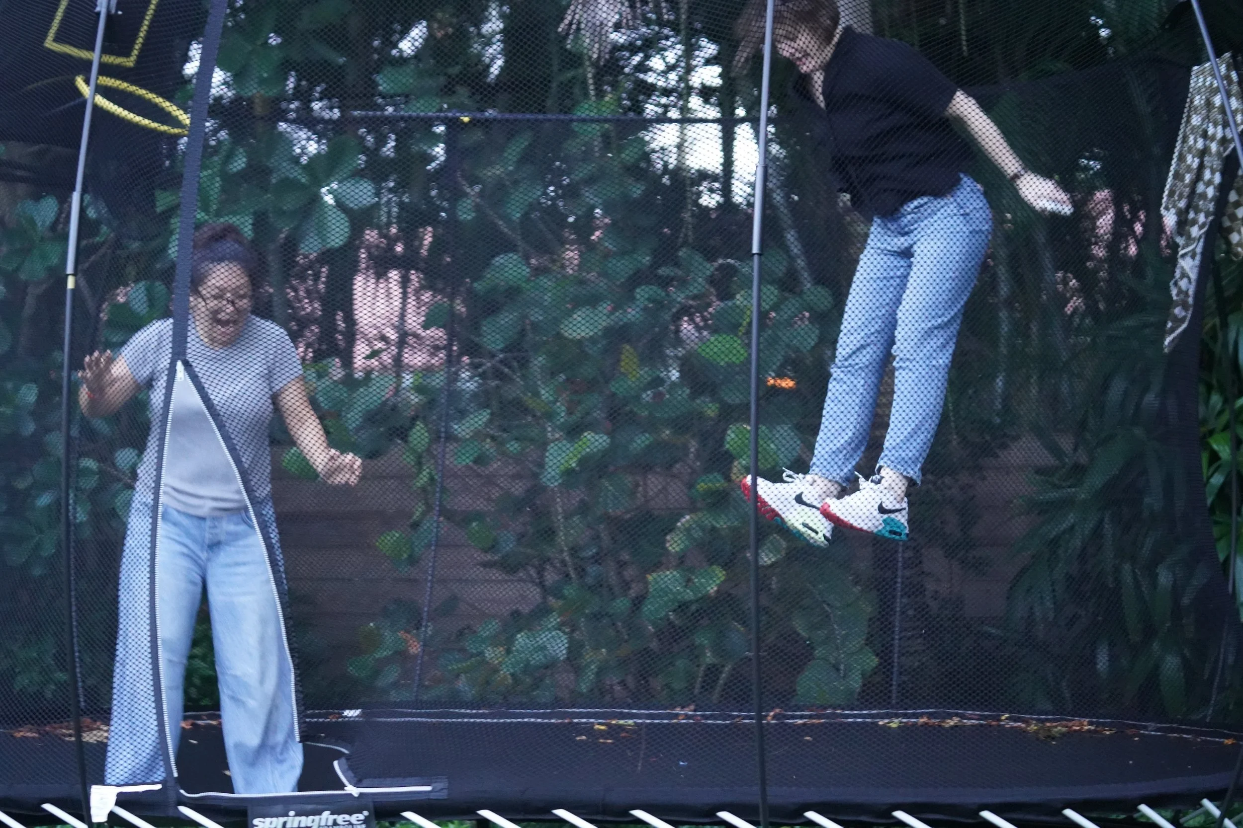 Two adults jump on a trampoline